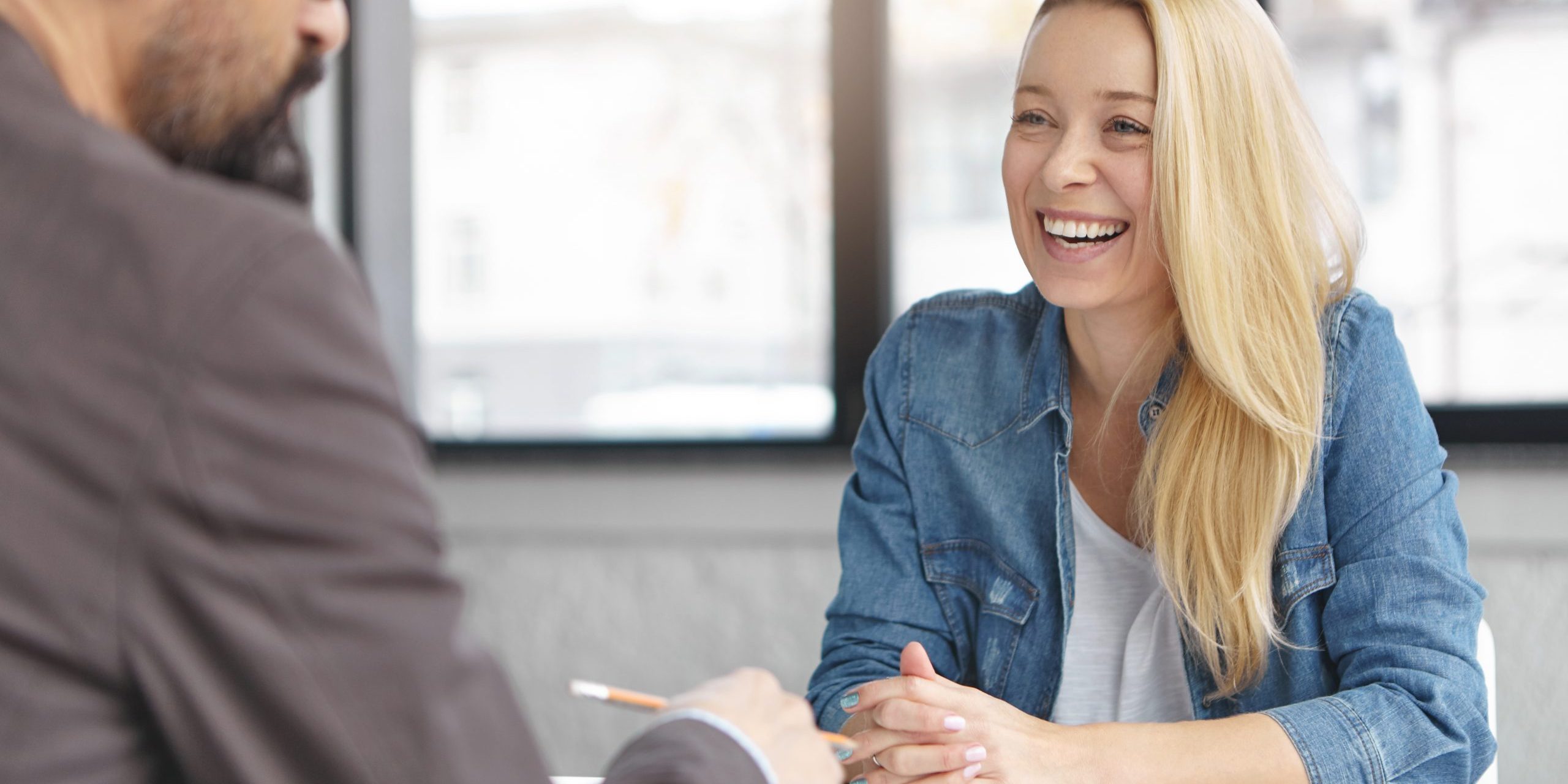 Happy blonde female manager in fashionable clothes has pleasant conversation with male colleague, discuss successful strategy for startup, chaeck list of affairs, consult new project together